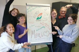 Les futurs bénévoles de l’association Accords à Aix-en-Provence tiennent un tableau rempli de mots bienveillants écrits ensemble pour clôturer leur formation à l’accompagnement des malades en soins palliatifs, en avril 2025.